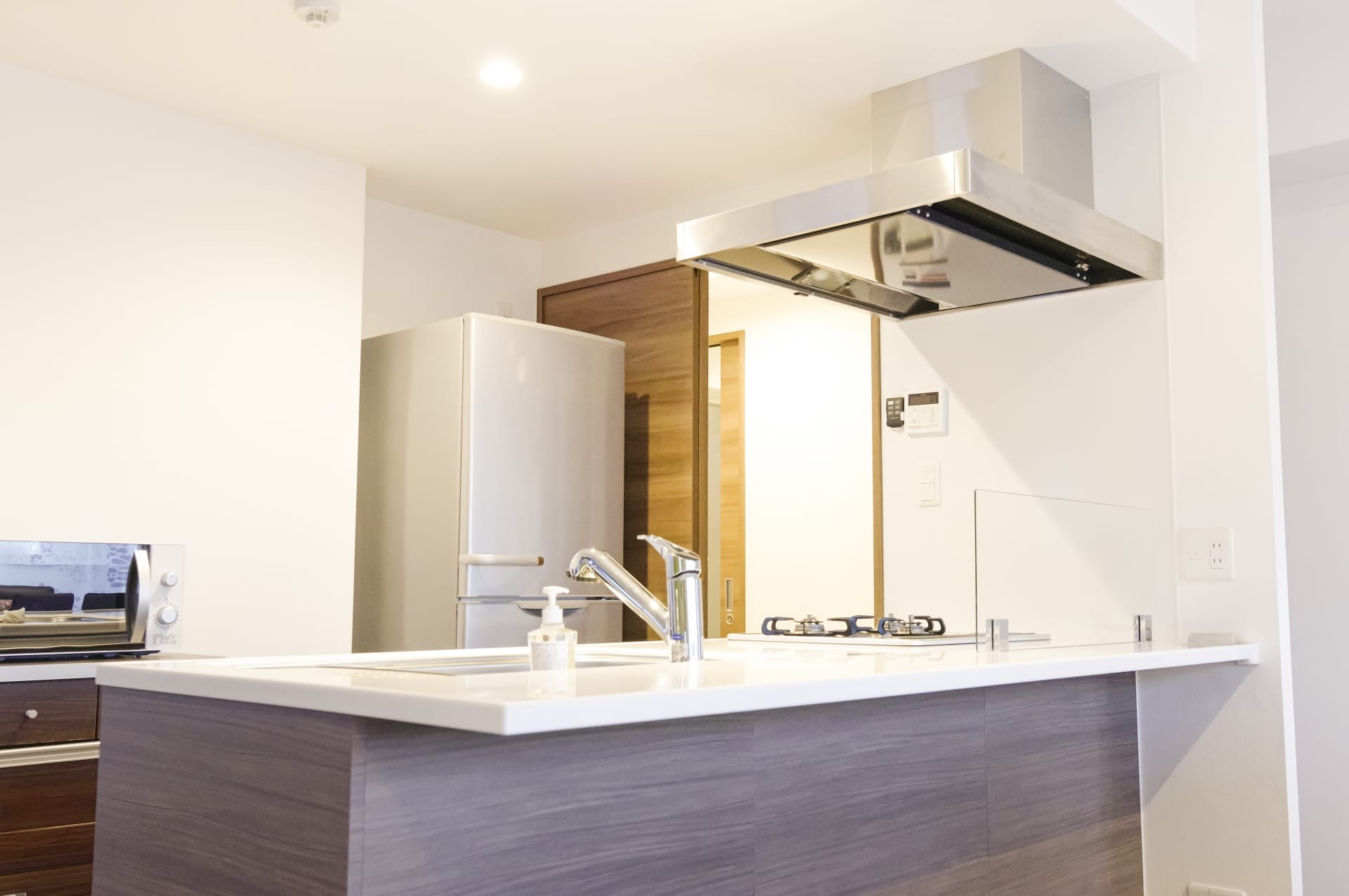 清潔感のある現代的なシステムキッチンで、対面型のカウンターと換気フードが設置されている