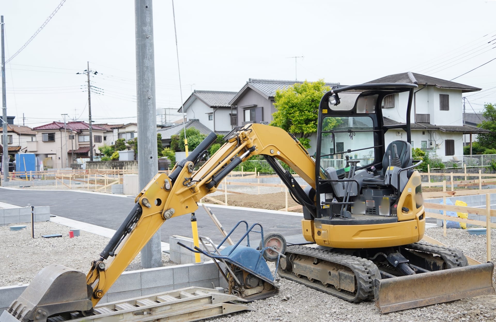 住宅街の一角で、小型ショベルカーが停車している建設現場の様子